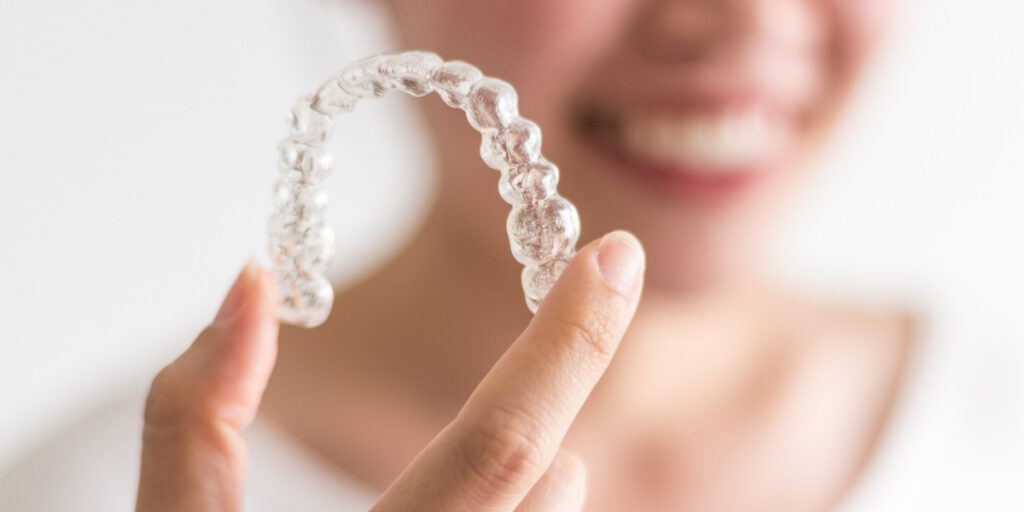 woman holds invisible dental braces 